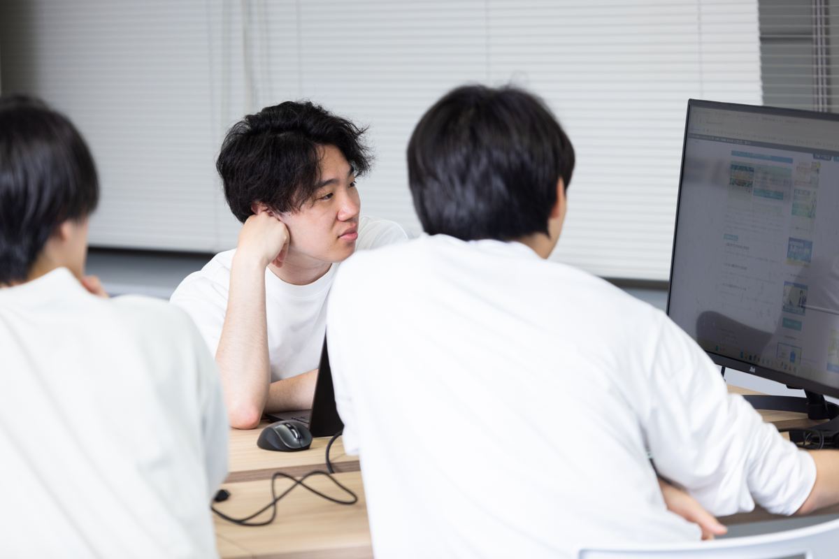 デスクで相談しながら話すメンバー